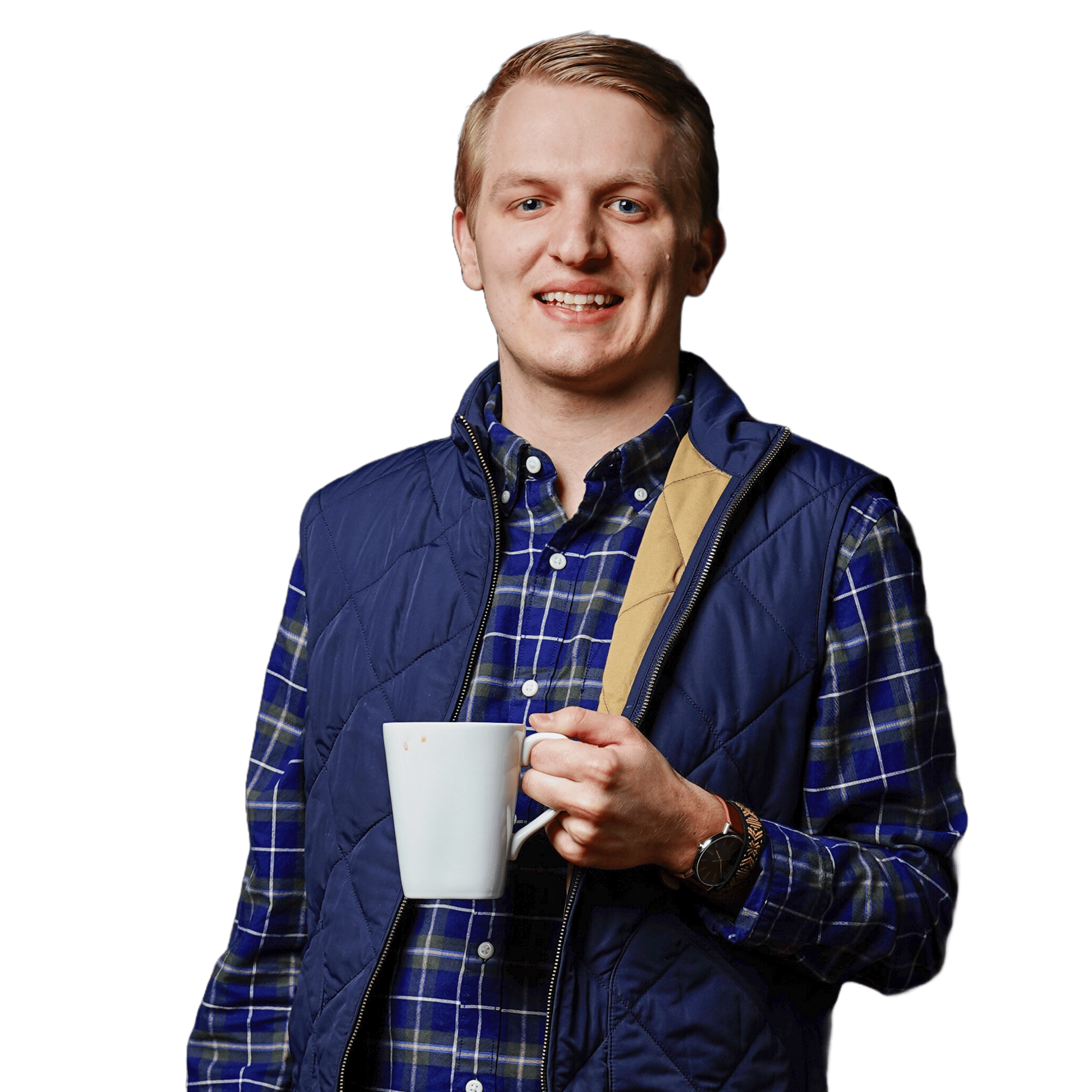 A person smiling, wearing a blue plaid shirt and a navy quilted vest, holding a white mug in one hand as they brainstorm custom software solutions.